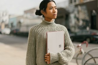 a woman standing on a sidewalk holding a laptop